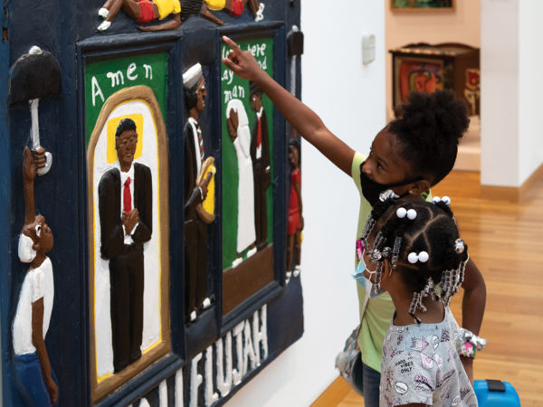 Two young children look at a carved mural in the galleries.