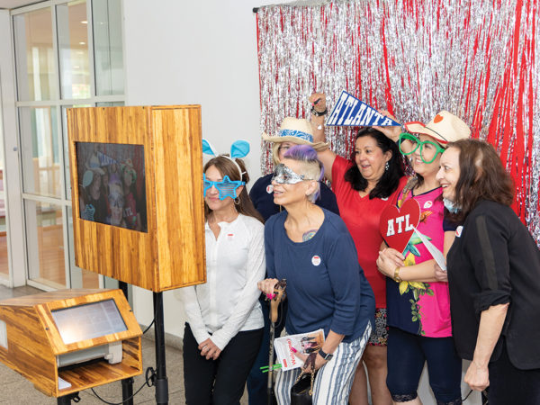 Visitors to the Lifelong Learning Celebration playfully pose in front of a photo booth.