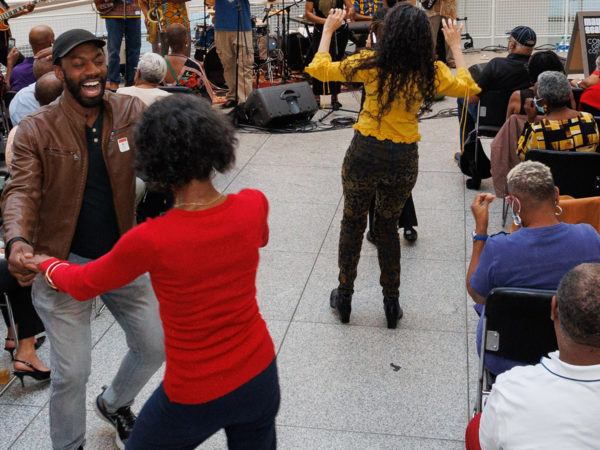 A band plays jazz music in the atrium while audience members dance in the aisle.